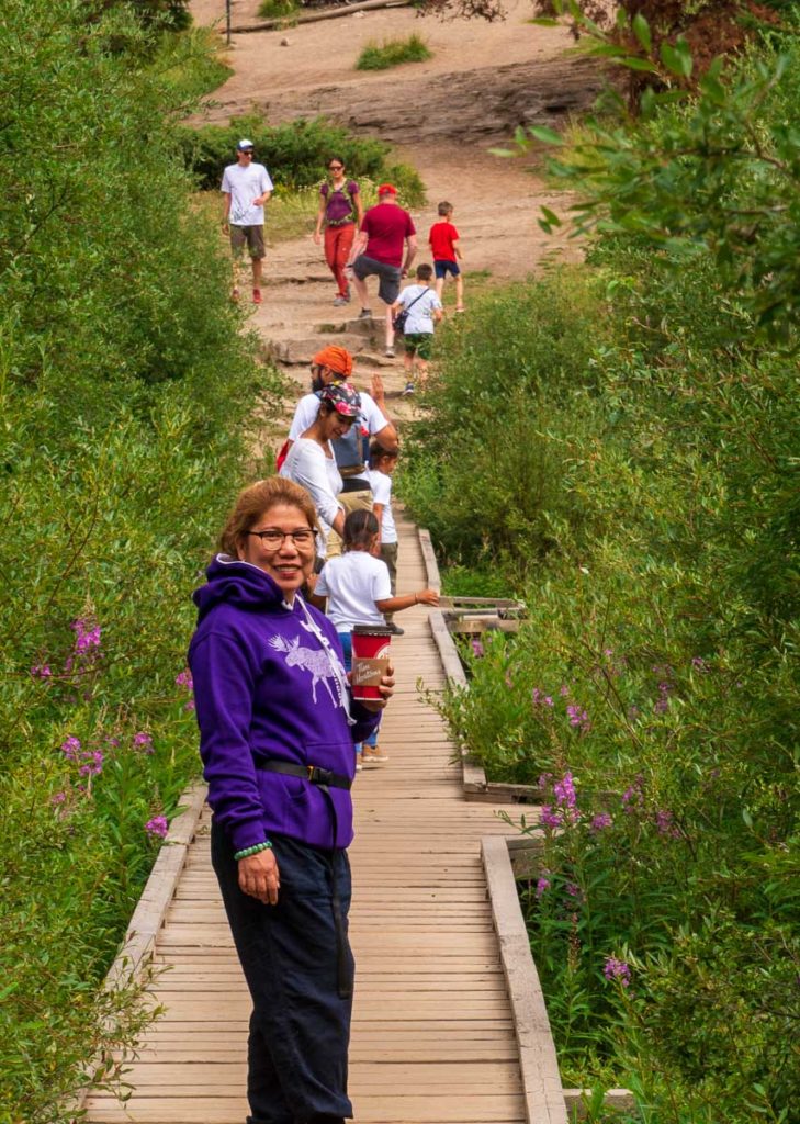 a photo of people crossing a wooden bridge at a hiking trail taken while hiking the valley of the five lakes in jasper national park Alberta Canada